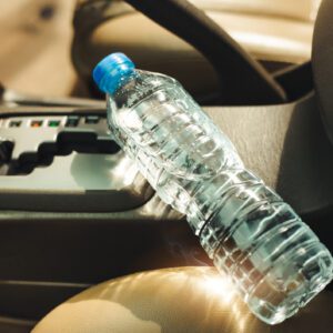 A plastic water bottle resting on a car's gear shift area.